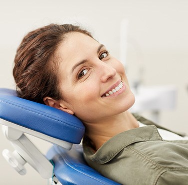 Woman leaning back in dental chair and smiling