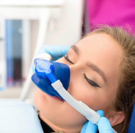 Young woman in dental chair with nitrous oxide sedation mask over her nose