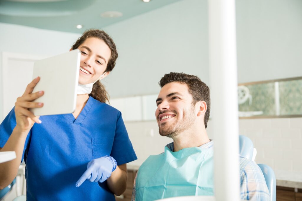 Man views tablet with dental hygienist